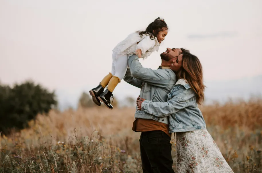 A man, his wife, and their daughter playing in a field